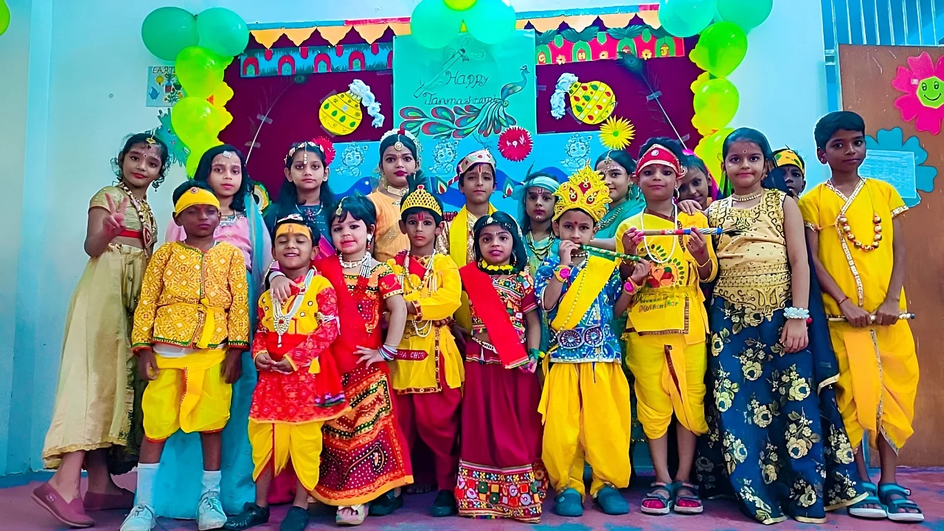 Young children dressed in colorful traditional attire for a Krishna Janmashtami celebration, posing with decorated backdrops.